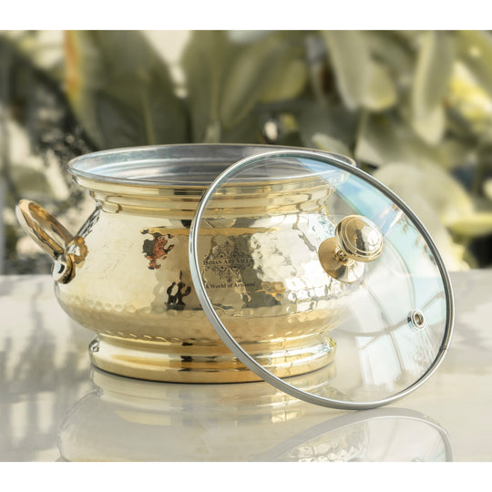 Decorative brass cooking pot with polished hammered design tin coating and transparent glass lid crafted for traditional use
