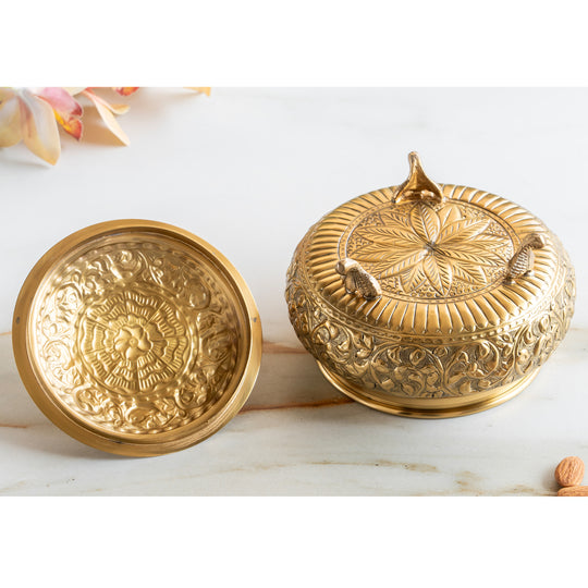 Pure brass handi with detailed embossed floral design curved body ornate lid and three small rounded legs for support