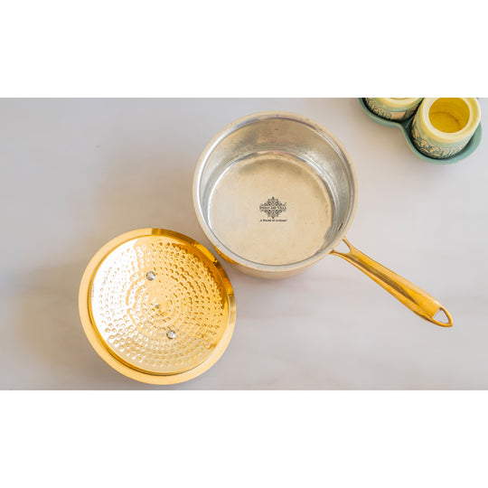 Wide hammered brass sauce pan with long handle lid and tin interior lining used for multipurpose cooking and kitchen tasks
