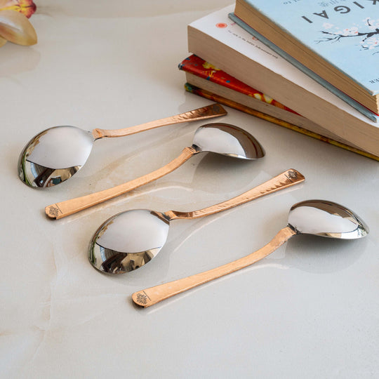 Finely crafted hammered copper spoons with detailed floral engravings perfect for serving soups stirring drinks or desserts.