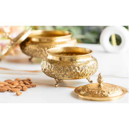 Embossed designer brass handi with round shape elegant lid and detailed floral patterns standing on three small legs