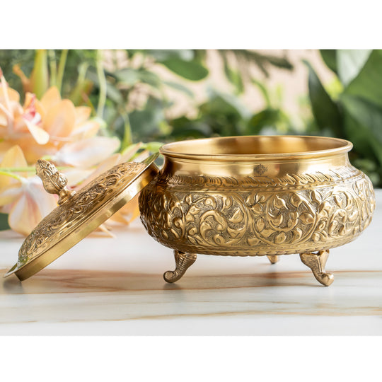 Handcrafted brass handi with embossed floral design and lid on three legs ideal for pooja decor and traditional gifting