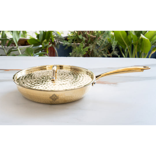 Brass pan with hammered texture lid extended handle polished exterior and tin lined interior classic cookware design