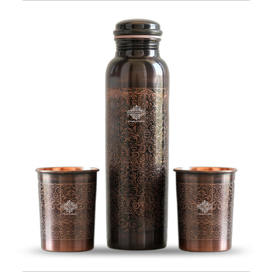 Antique copper water bottle with embossed floral design, paired with matching glasses in a softly lit home environment.
