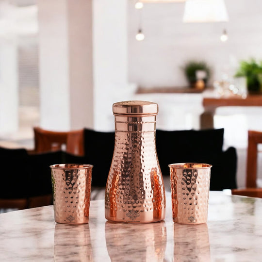 Luxurious hammered copper drinkware set, featuring a bottle and tumblers, perfect for décor and daily use.