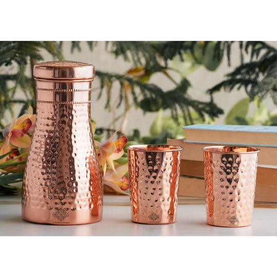 Luxurious hammered copper drinkware set, featuring a bottle and tumblers, perfect for décor and daily use.