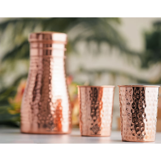 Luxurious hammered copper drinkware set, featuring a bottle and tumblers, perfect for décor and daily use.