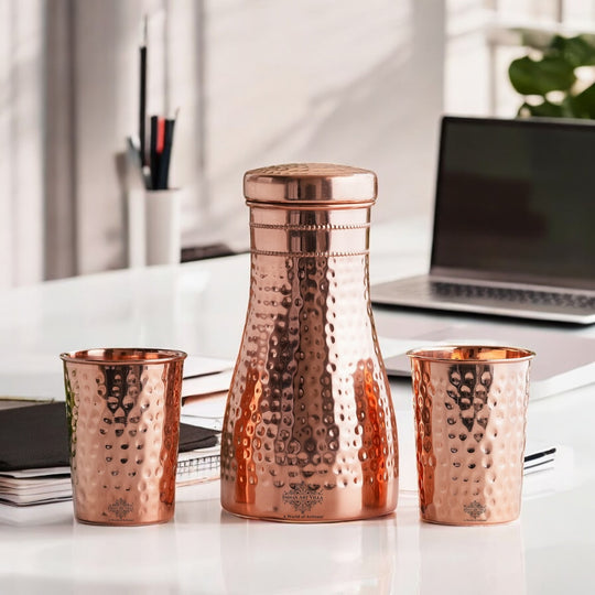 Luxurious hammered copper drinkware set, featuring a bottle and tumblers, perfect for décor and daily use.