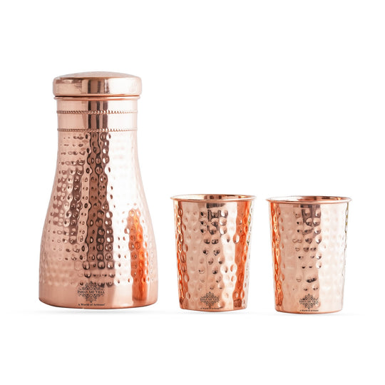 Luxurious hammered copper drinkware set, featuring a bottle and tumblers, perfect for décor and daily use.