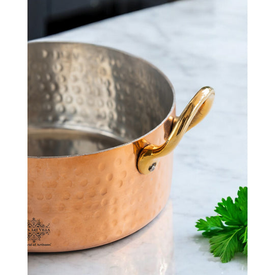 Indian Art Villa’s copper handi with a decorative hammered finish and robust brass handles perfect for modern kitchens.