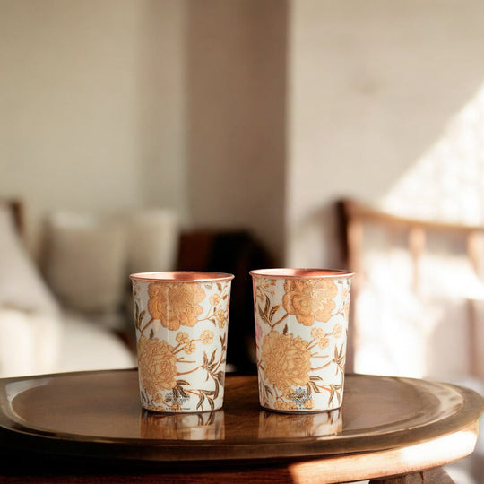 Floral artwork shines on each copper glasswear for drinking water included in this Indian Art Villa set of 2
