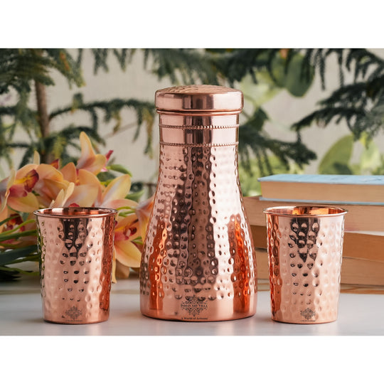 Luxurious hammered copper drinkware set, featuring a bottle and tumblers, perfect for décor and daily use.