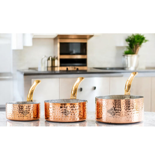 Classic copper saucepan with a shiny interior, hammered exterior, and solid brass handle for easy handling.