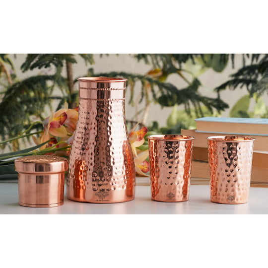 Luxurious hammered copper drinkware set, featuring a bottle and tumblers, perfect for décor and daily use.