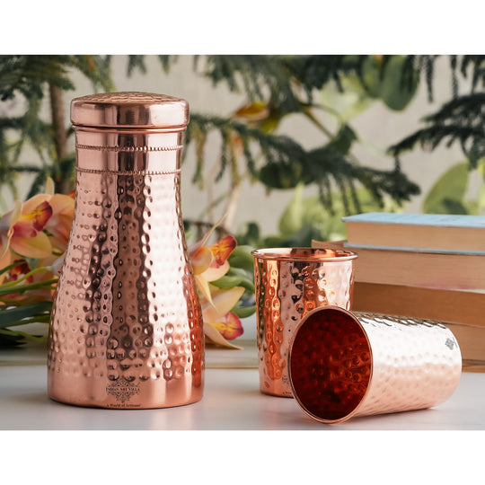 Luxurious hammered copper drinkware set, featuring a bottle and tumblers, perfect for décor and daily use.