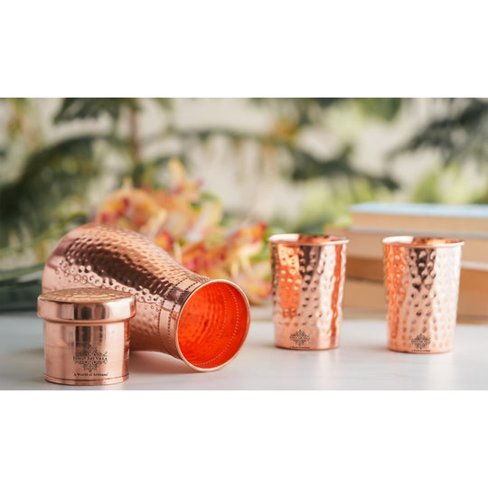 Luxurious hammered copper drinkware set, featuring a bottle and tumblers, perfect for décor and daily use.