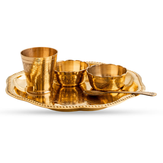 Set of gold-colored metal utensils including a tray, cups, bowls, and a spoon on a white background.