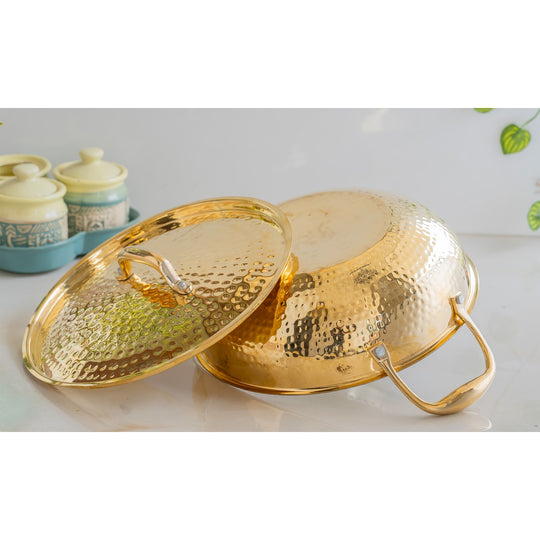Classic brass cooking vessel hammered surface with tin interior secure lid and twin handles in timeless golden tone