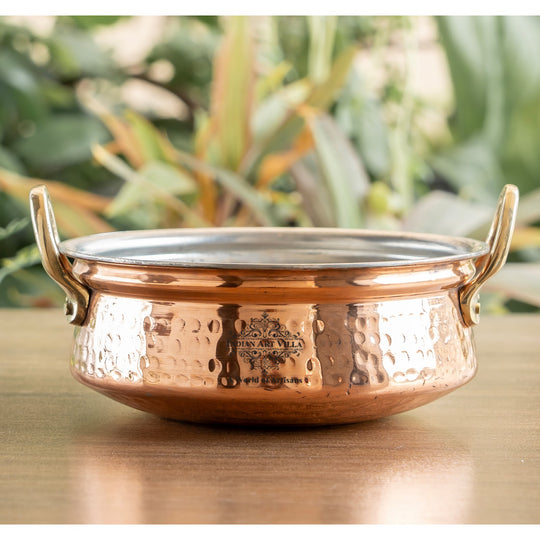 Decorative hammered copper handi with handle and tin lining, perfect for creating a traditional dining atmosphere.
