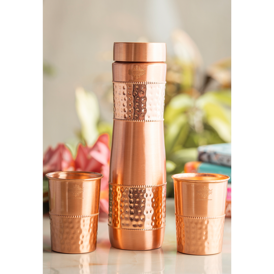 Crafted by Indian Art Villa, this copper drinkware set features a stylish hammered finish, complete with a bottle and two elegant glasses.