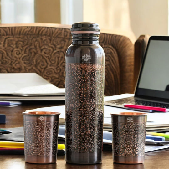 Antique copper water bottle with embossed floral design, paired with matching glasses in a softly lit home environment.