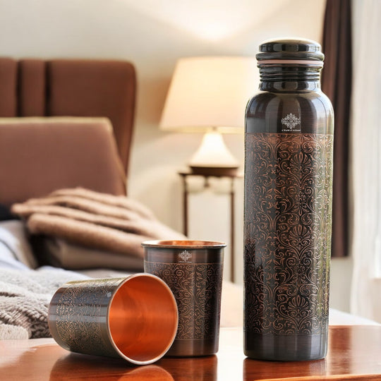 Antique copper water bottle with embossed floral design, paired with matching glasses in a softly lit home environment.