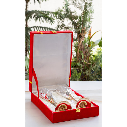 Red gift box with a white interior containing two wooden spoons on a white surface with a blurred green background.