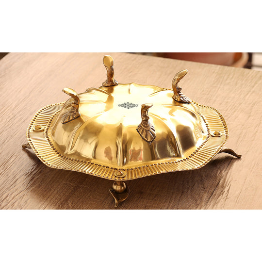 Round brass serving tray crafted with curved rim ornate leaf decor and pedestal legs in a radiant golden appearance